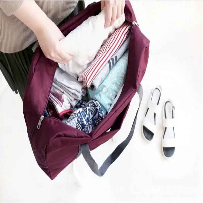 Open foldable travel duffel bag with clothing packed inside.